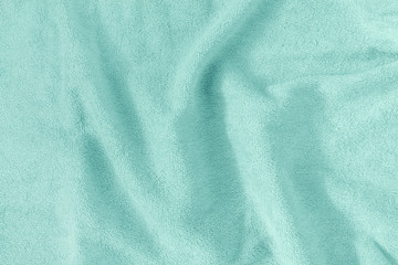 The texture of a crumpled terry towel. Empty light turquoise background.