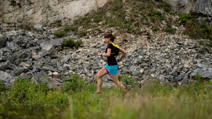 Naklejka na ściany i meble Girl athlete runs a long trail running on a beautiful area along the cliff. Healthy lifestyle