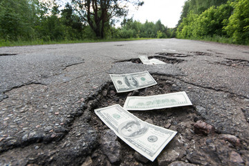 Dollar bills in the potholes on road