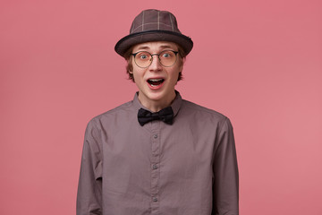 Stupefied guy looks with astonishment into camera, being amazed with incredible unbelievable...