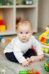 little happy boy 6-7 months playing in a bright children's room with a designer 