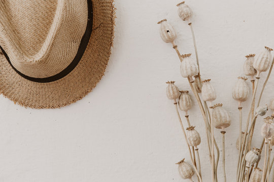 Straw hat with dried poppy, creamy background, minimal lifestyle