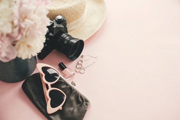 Obraz na płótnie Canvas Hello summer. International womens day. Stylish photo camera, sunglasses, jewelry,straw hat, cosmetics,bag pink and white peonies bouquet on pink paper with space for text.