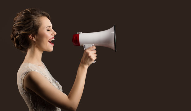 Woman holding megaphone in hand and screaming. Dark background.