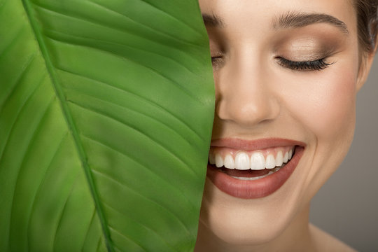 Portrait Of Woman And Green Leaf. Organic Beauty. Gray Background.