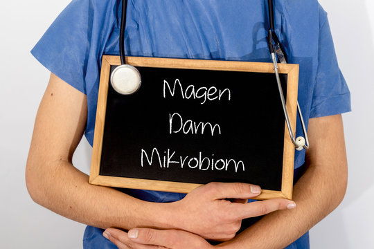 Doctor shows information on blackboard: Magen Darm Mikrobion.  Medical concept.