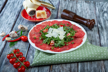 close-up carpaccio meat with arugula and slices of parmesan cheese
