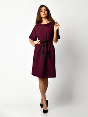 Young beautiful woman posing in new fashion casual purple winter dress smiling on white