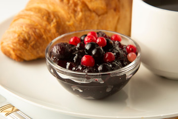 Close up berry jam and croissant on white table. French croissant. Fresh buns meal, snack. Isoalted with copy space. Pastry and dessert.