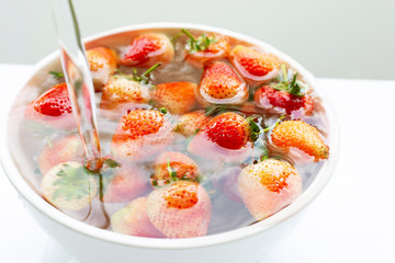 Strawberries soaked in water. Washing fresh fruit. on white.