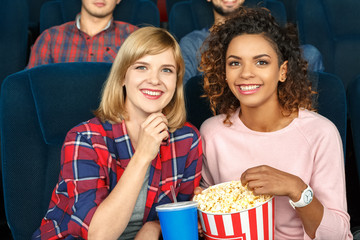 Enjoying a great comedy. Two beautiful female friends laughing happily watching a film in the local movie theater