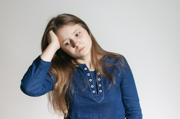 a teen girl in a blue dress with a headache holding her head with her right arm and not looking at a camera