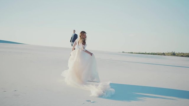 magnificent happy bride runs to her beloved, girl in a chic long white dress turns to the camera and smiles, happy before the wedding day, queen of the desert and her beloved husband