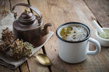 Healthy tea with Iceland moss. Retro tea kettle and mortar on wooden board.