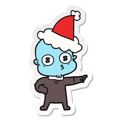 sticker cartoon of a weird bald spaceman wearing santa hat