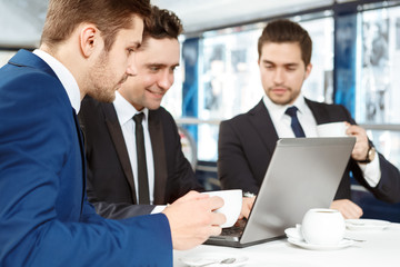 This might work. Business team of three men using laptop on a meeting over a cup of coffee