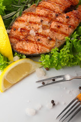 Salmon steak grilled with lemon.Sea salt.On leaf of salad.Closeup