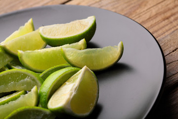 Fresh lime.Close up sliced limes on black plate.Wooden table.Copy space.