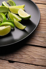 Fresh lime.Close up sliced limes on black plate.Wooden table.Copy space.