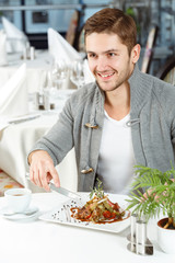 About to eat this. Young cheerful man enjoying his lunch at the local restaurant looking away smiling joyfully