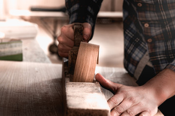 Vintage carpenter working on wood using wood retro vintage old ancient planer. Workshop background.