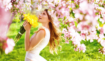 Beauty Portrait of Beautiful Young Brunette Woman In Nice Spring Dress With A Bouquet Of Tulips.Spring Style. Beautiful Spring Garden. Fashion Spring Summer Photo. Fashion and style concept. Long edge