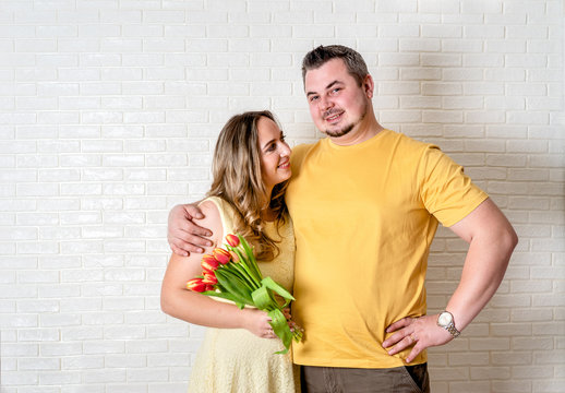 Portrait of happy couple, husband and wife with spring flower bouquet