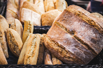 Homemade breads cooked in wood-fired oven as formerly yummy. Delicious large breads packed with flour in a basket