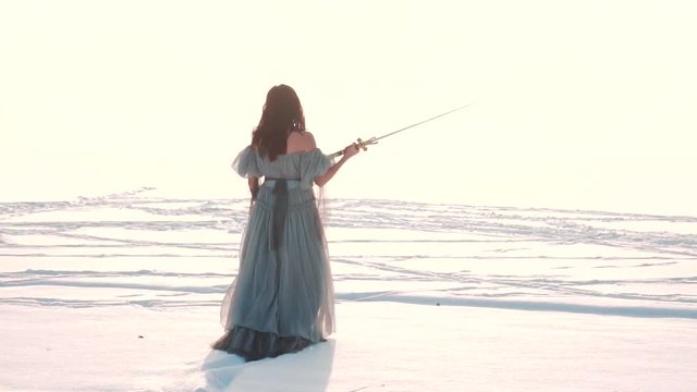 brave girl walks in snow in long gray vintage dress with open shoulders, ady raises scary sharp silver sword upwards, dark elf fearlessly goes into battle, fantasy style with arctic polar nature