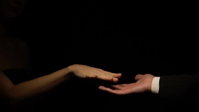 Man in suit and woman stroking hands isolated on black background, relationship