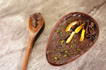 Chocolate egg with filling for Easter on wooden background. Easter egg stuffed with chocolate and coffee.