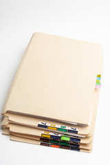 A stack of color-coded and numbered yellow file folders containing sheets of papers, files and...