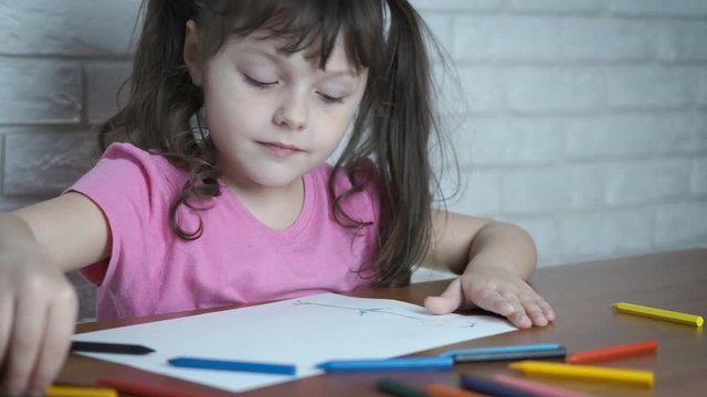 Beautiful little girl draws. Adorable little girl draws with multi-colored wax crayons.