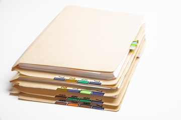 A stack of color-coded and numbered yellow file folders containing sheets of papers, files and documents set on a white background.