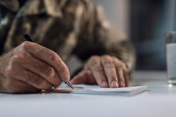 Close up of senior soldier taking notes.