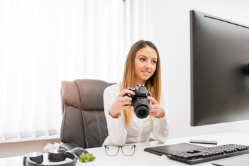 Attractive young girl in a photo studio editing photos.