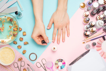 Concept of nail art. Woman gives herself a manicure on a white table