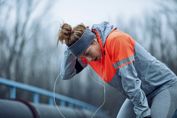 Exhausted female runner taking a break outdoors.