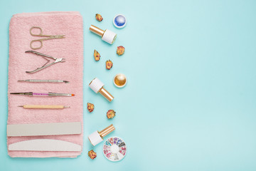 A set of cosmetic tools for manicure and pedicure on a blue background. Gel polishes, nail files and nippers and top view. Composition for a card with a place for text.