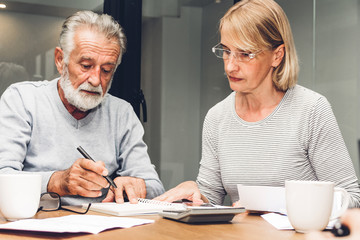 Senior couple reading documents and calculating bills to pay in living room at home.Retirement couple and loan bankruptcy money concept