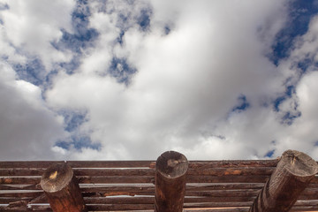 Blue sky with clouds over exposed vigas and latillas, adobe exterior construction details,...
