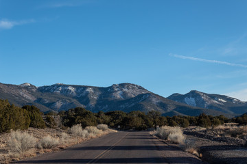 Road in winter desert New Mexico, snowy mountains, American Southwest, horizontal aspect