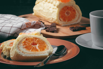 Fototapeta na wymiar Sweet roll with whipped cream and tangerine filling and a cup of tea