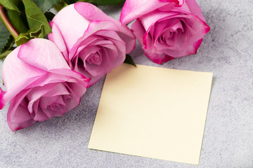 bouquet of pink roses and a blank note on the table