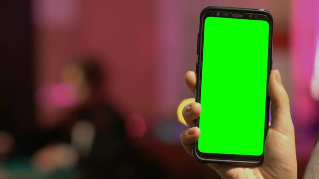 Hand holding smartphone with green screen, online casino concept, gambling