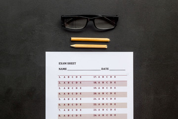 On the exam. Exam sheet, answer near glasses and pencil on black background top view