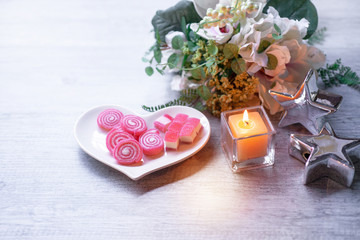 Fototapeta na wymiar Sweet jelly in heart shaped plate for valentine's day with candle, silver star on wood background