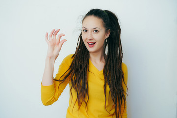 Beautiful girl with dreadlocks and in a yellow bright sweater shows her small size and smiles in...