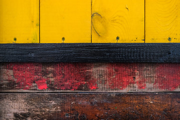 Wooden old painted colorful background. Yellow with a dirty red, separated by a black board.