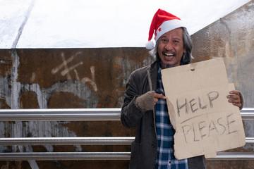 Homeless man in Santa Claus hat holding cardboard text